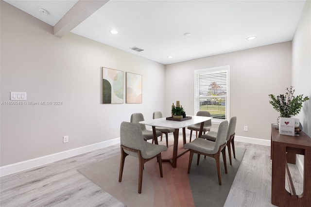 dining space featuring light wood-type flooring and beam ceiling