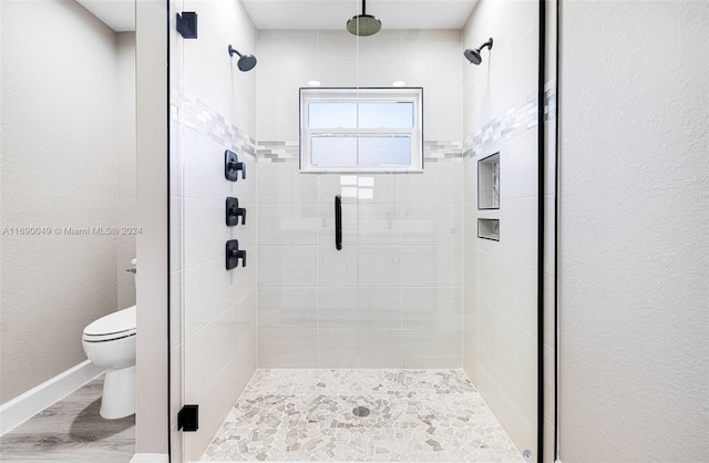 bathroom with toilet, hardwood / wood-style floors, and a shower with door