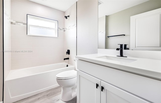 full bathroom featuring wood-type flooring, tiled shower / bath combo, toilet, and vanity