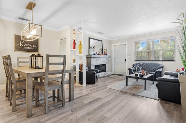 living room featuring a stone fireplace, hardwood / wood-style floors, ornamental molding, and a textured ceiling