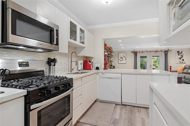 kitchen featuring stainless steel appliances, light hardwood / wood-style floors, sink, ornamental molding, and white cabinets