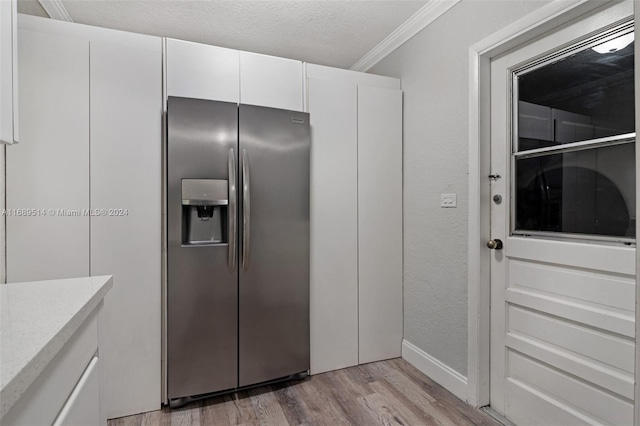 kitchen featuring light hardwood / wood-style floors, ornamental molding, a textured ceiling, white cabinets, and stainless steel fridge with ice dispenser