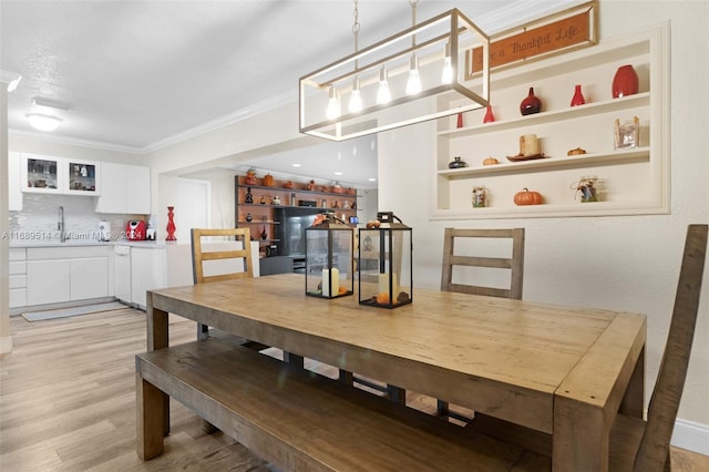 dining space with ornamental molding, light wood-type flooring, and sink