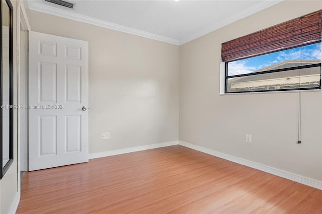 empty room with a textured ceiling, ornamental molding, and light hardwood / wood-style flooring