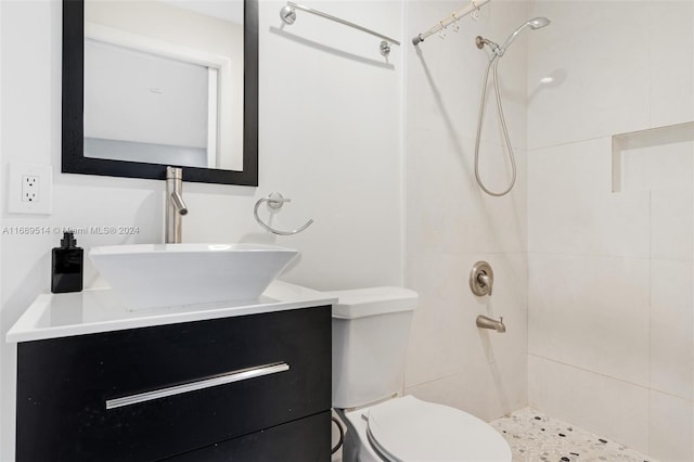 bathroom with toilet, vanity, and tiled shower