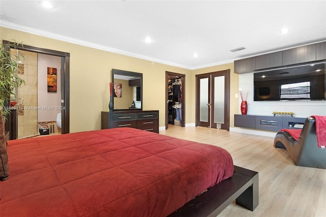 bedroom featuring a spacious closet, french doors, ornamental molding, and light hardwood / wood-style flooring