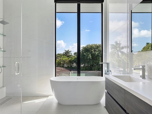 bathroom featuring a tub, tile patterned floors, expansive windows, and vanity