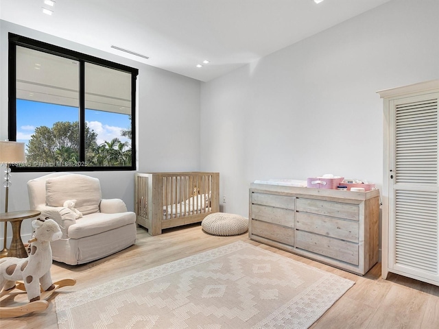 bedroom featuring a crib and light wood-type flooring