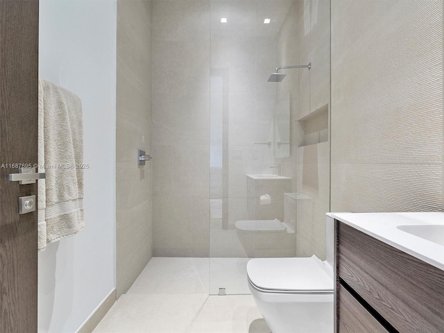 bathroom featuring toilet, vanity, a tile shower, and tile patterned flooring