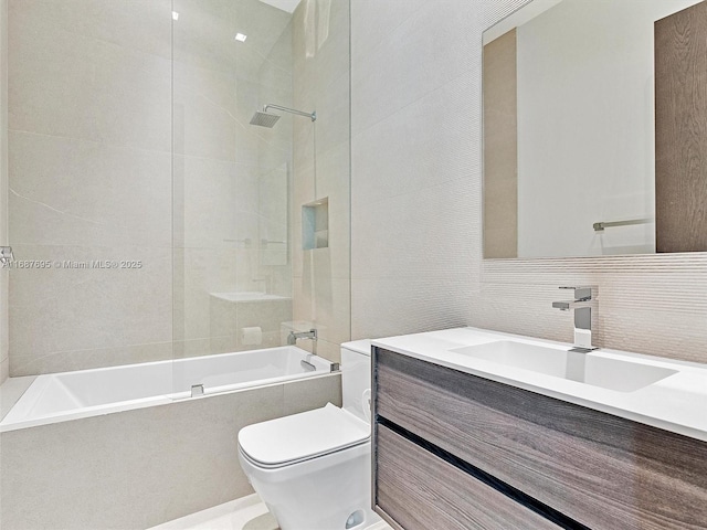 full bathroom featuring tiled shower / bath combo, toilet, tile walls, and vanity