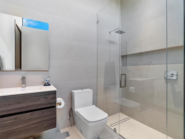 bathroom with tile patterned flooring, tile walls, toilet, a shower with shower door, and vanity