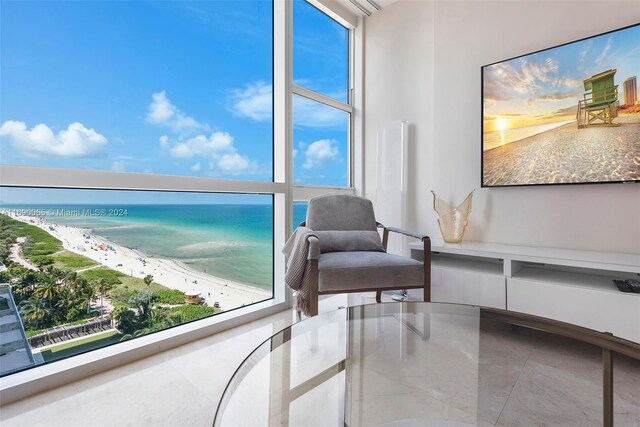 living area with a beach view, a water view, and a wealth of natural light