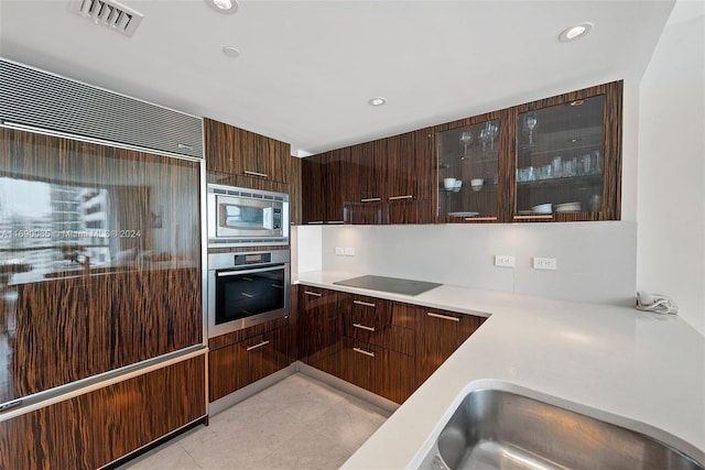 6801 Collins Ave Unit 1215, Miami Beach, FL 33141 - kitchen featuring stainless steel appliances, modern cabinets, light countertops, glass insert cabinets, and recessed lighting