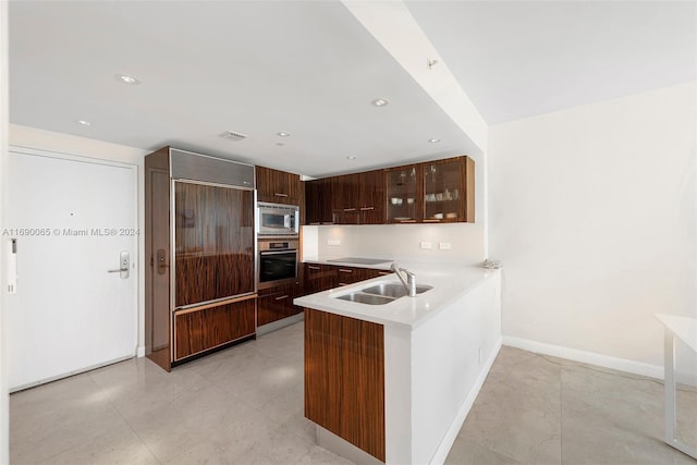 6801 Collins Ave Unit 1215, Miami Beach, FL 33141 - kitchen with built in appliances, modern cabinets, glass insert cabinets, light countertops, and a peninsula