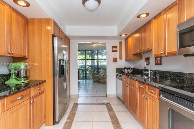 kitchen featuring dark stone counters, appliances with stainless steel finishes, sink, and light tile patterned floors