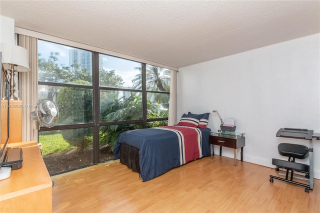 bedroom with hardwood / wood-style flooring, a textured ceiling, and floor to ceiling windows