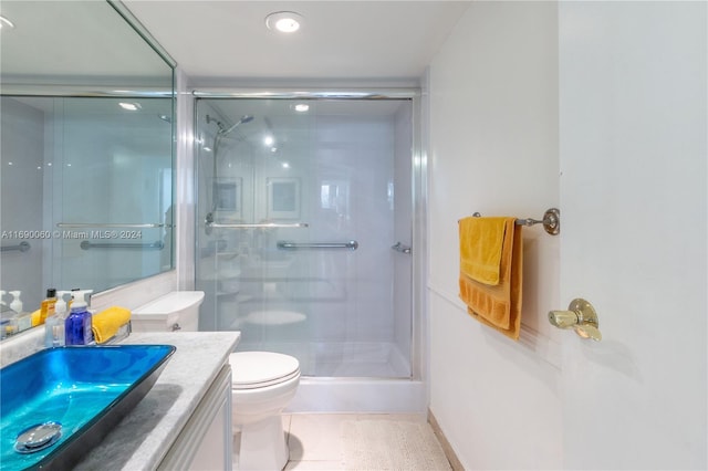 bathroom with toilet, vanity, tile patterned flooring, and a shower with door