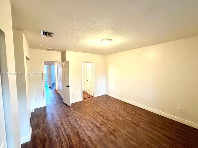 empty room featuring dark hardwood / wood-style floors and a textured ceiling