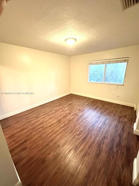 empty room featuring a textured ceiling and dark hardwood / wood-style floors