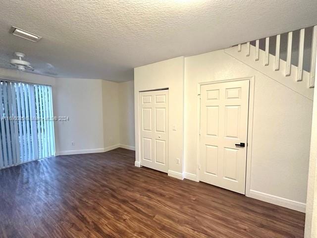 empty room with dark wood-type flooring, a textured ceiling, and ceiling fan