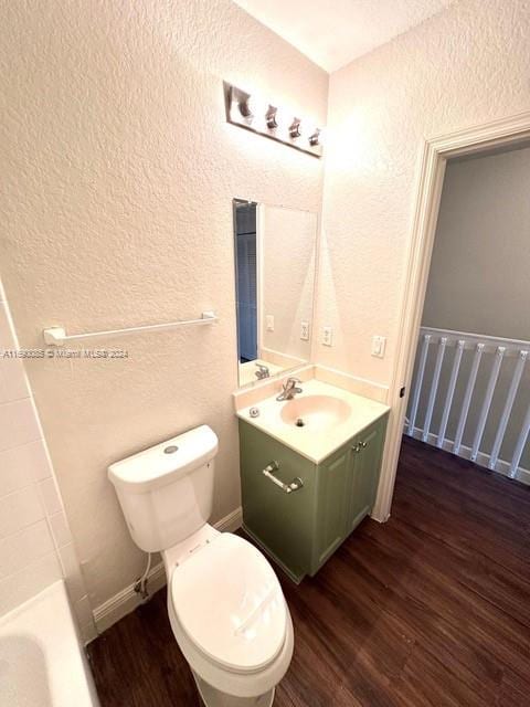 bathroom with a tub, vanity, hardwood / wood-style flooring, and toilet