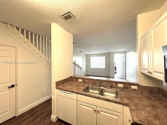 kitchen with white cabinetry, a textured ceiling, dark hardwood / wood-style flooring, sink, and dishwasher