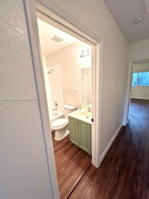 full bathroom featuring toilet, vanity, hardwood / wood-style floors, and  shower combination