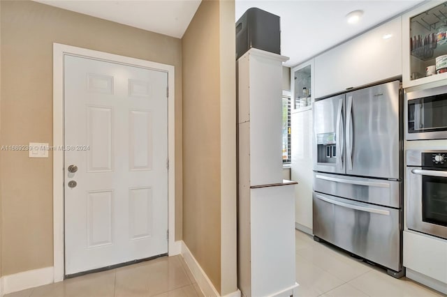21300 San Simeon Way Unit K2, Miami, FL 33179 - kitchen featuring appliances with stainless steel finishes, light tile patterned floors, white cabinets, glass insert cabinets, and baseboards