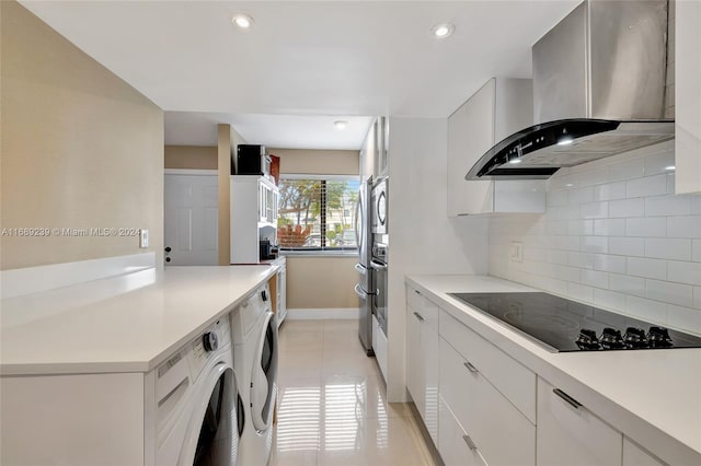 kitchen with black electric cooktop, wall chimney exhaust hood, white cabinetry, and tasteful backsplash