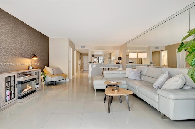 21300 San Simeon Way Unit K2, Miami, FL 33179 - living room featuring an accent wall, a glass covered fireplace, wallpapered walls, and light tile patterned floors
