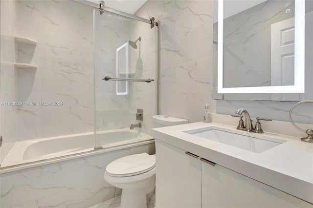 full bathroom with tile walls, vanity, tiled shower / bath, and toilet