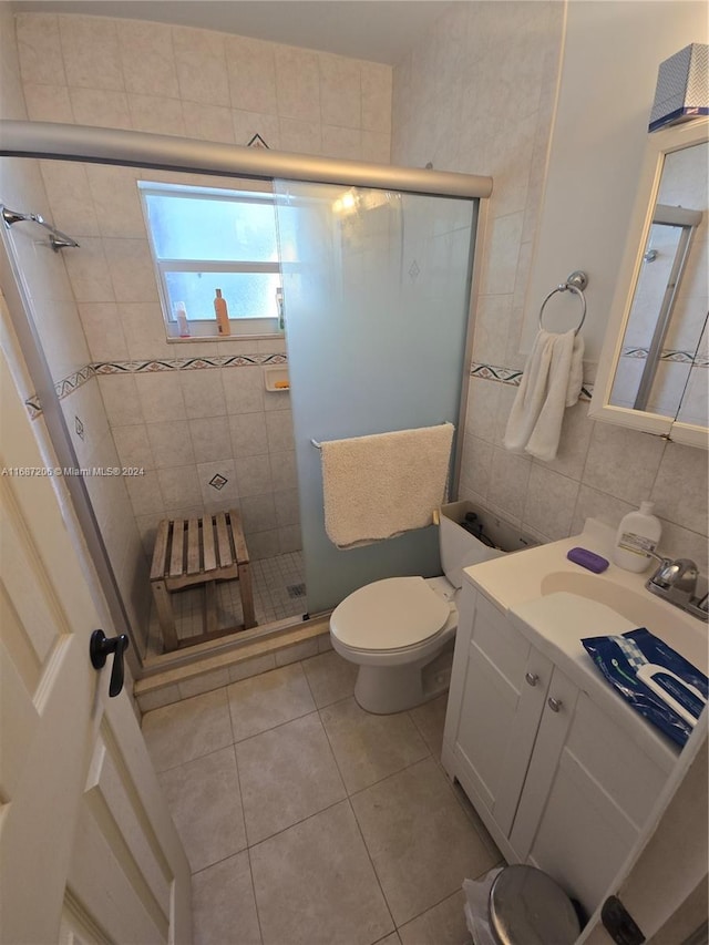 bathroom featuring tile patterned flooring, vanity, an enclosed shower, toilet, and tile walls