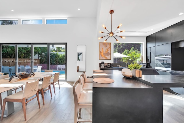 dining room with light hardwood / wood-style floors, a high ceiling, and an inviting chandelier