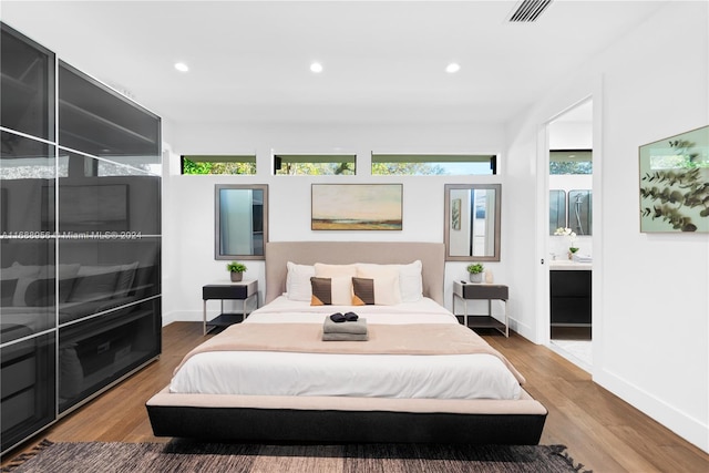 bedroom with connected bathroom and hardwood / wood-style flooring