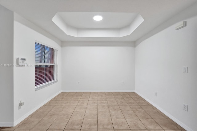 tiled empty room featuring a raised ceiling