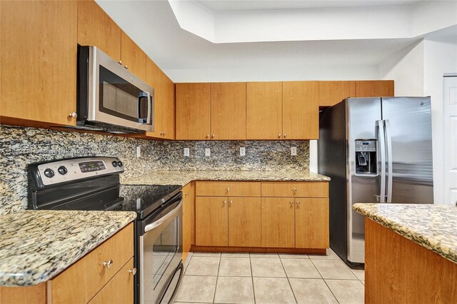 kitchen with stainless steel appliances, light tile patterned floors, light stone counters, and tasteful backsplash