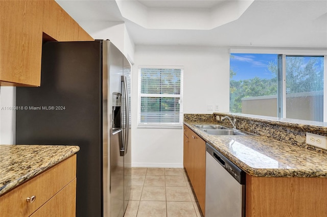 kitchen with light tile patterned flooring, sink, kitchen peninsula, appliances with stainless steel finishes, and dark stone counters