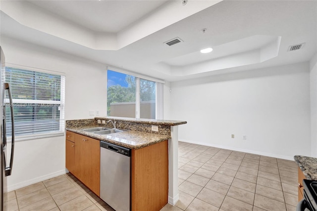 kitchen with kitchen peninsula, stainless steel dishwasher, sink, and a tray ceiling