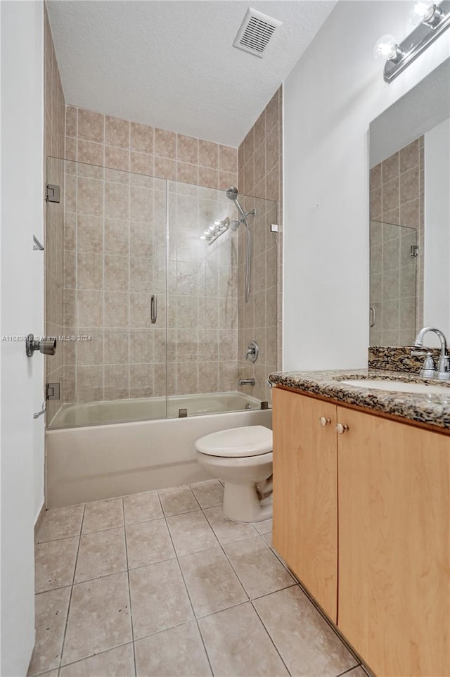 full bathroom with toilet, vanity, a textured ceiling, and tile patterned flooring