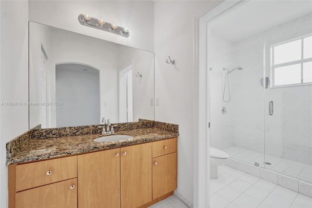 bathroom featuring vanity, a shower with door, tile patterned floors, and toilet