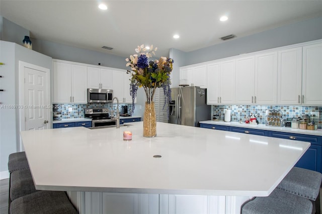 kitchen featuring tasteful backsplash, a kitchen breakfast bar, a spacious island, appliances with stainless steel finishes, and white cabinetry