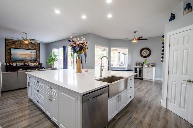 kitchen featuring wood-type flooring, sink, a kitchen island with sink, stainless steel dishwasher, and white cabinetry