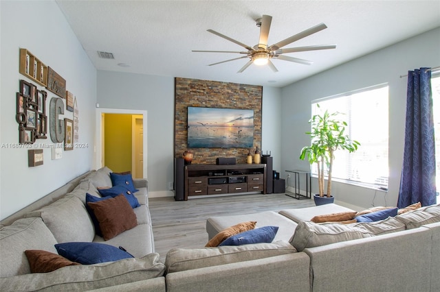 living room featuring ceiling fan, a textured ceiling, and light wood-type flooring