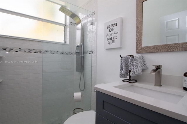 bathroom with tiled shower, vanity, and toilet