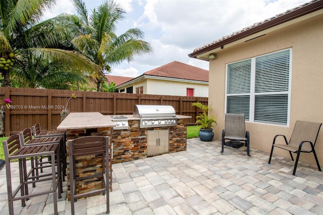 view of patio / terrace with an outdoor kitchen, a grill, and a bar