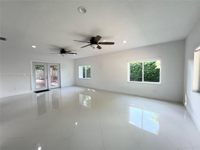 tiled spare room featuring french doors, a textured ceiling, ceiling fan, and a healthy amount of sunlight