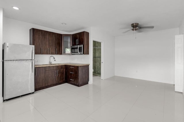 kitchen with sink, light tile patterned floors, stainless steel appliances, and dark brown cabinets