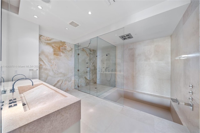 bathroom with a tile shower, sink, and tile walls