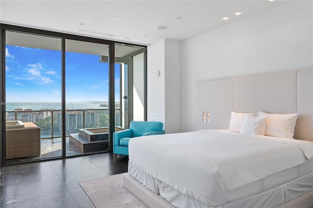 bedroom featuring access to outside, expansive windows, and a water view