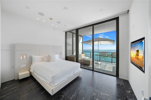 bedroom with expansive windows, a water view, and access to exterior